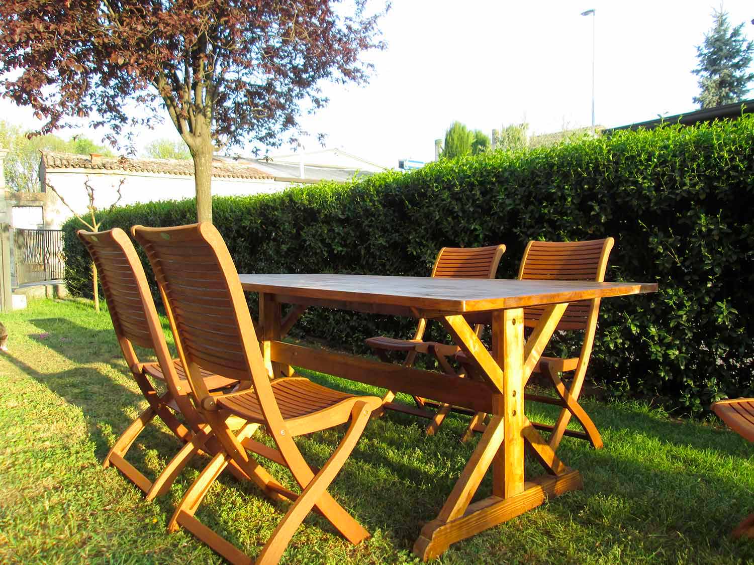 Tavolo e sedie in legno collocati in un giardino verde